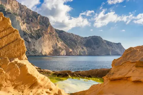 Acantilados dorados y mar azul en Ibiza, un rincón que evoca la magia de Atlantis Ibiza.