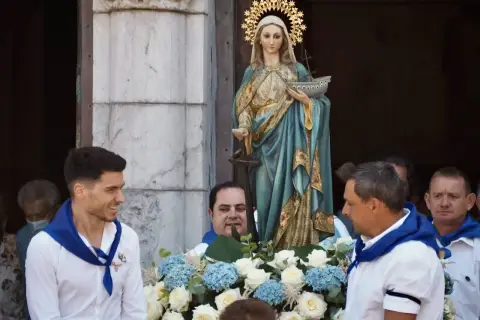 Procesión de la Virgen de la Guía, con hombres portando la imagen adornada con flores.